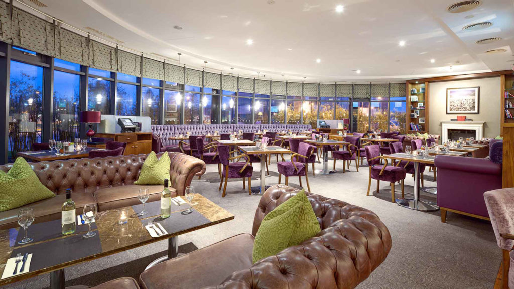 The interior of the New Yorker Bar at the Cork International Hotel with leather and velvet seating and a curved wall of windows