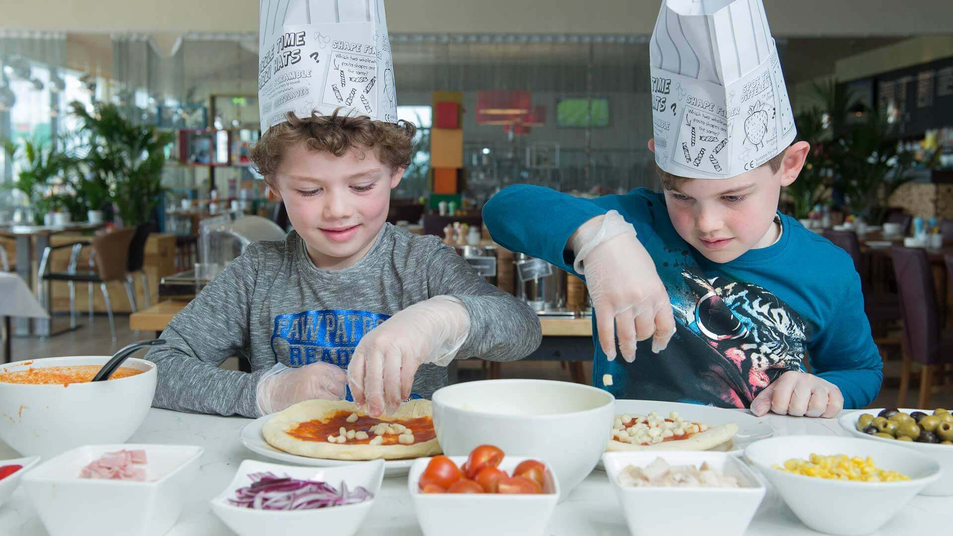 Kid's pizza making at Cork Airport Hotel; two happy children add toppings to their own pizzas
