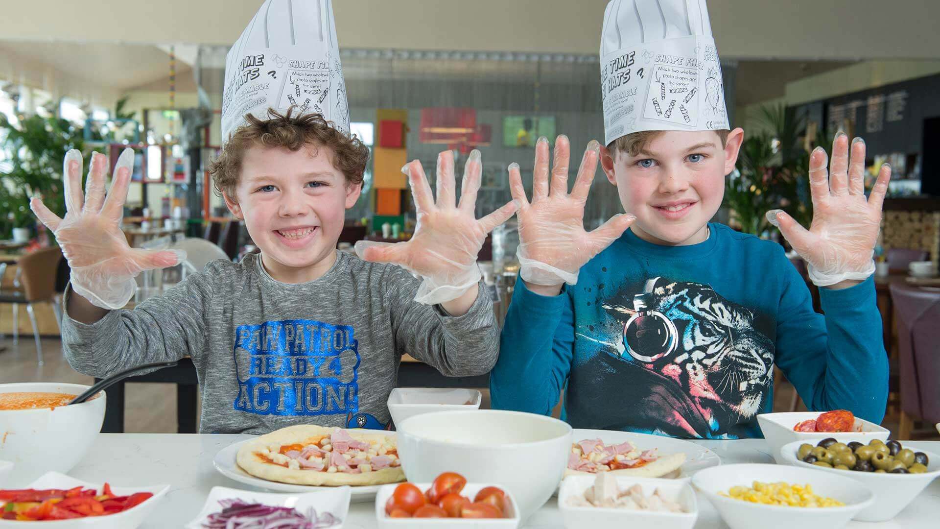 Two children holding up their hands before they start making their own pizzas from a selection of yummy ingredients