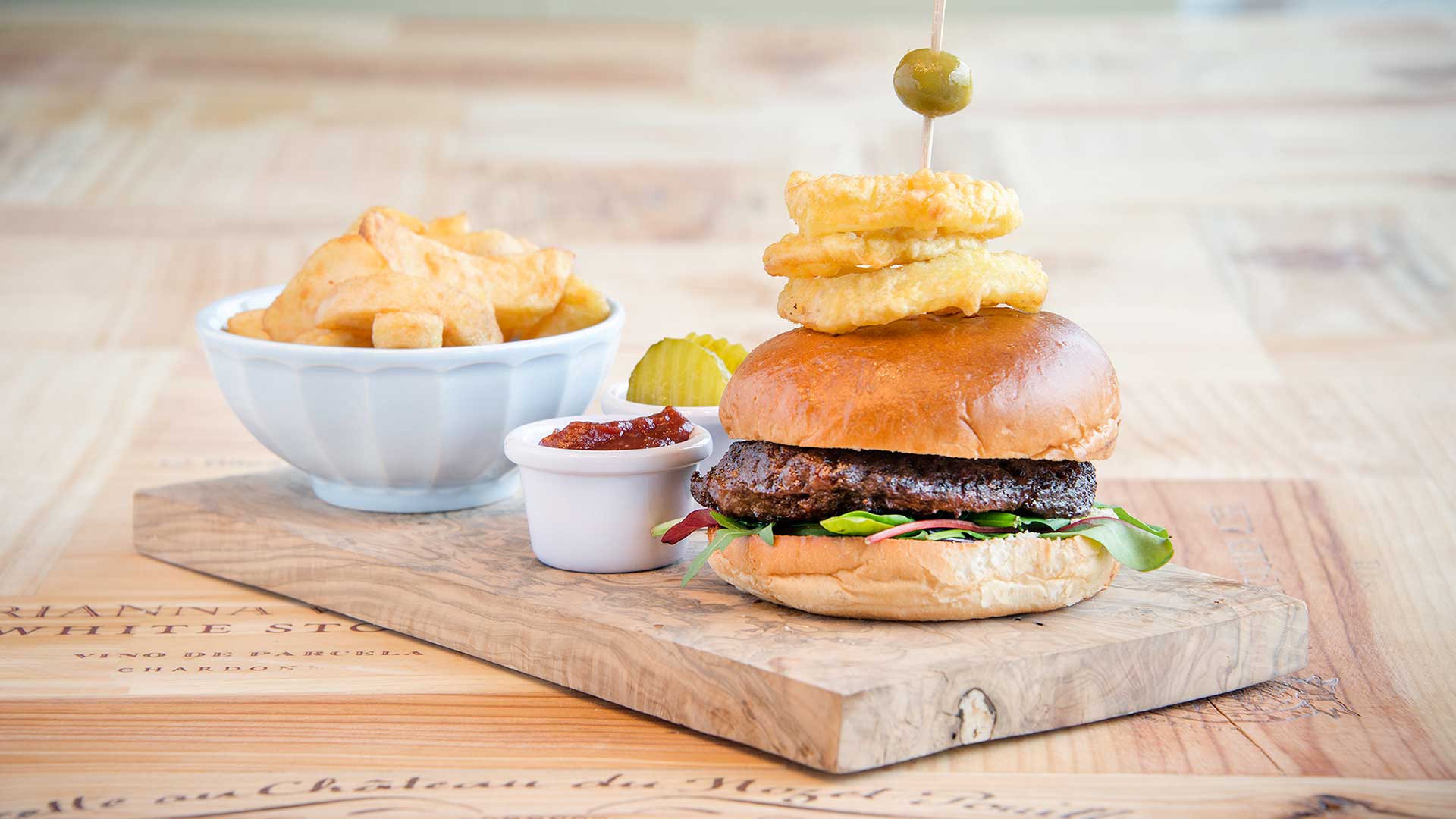 Burger garnished with onion rings and crispy chips, one of the dishes available from the Cork Airport Hotel