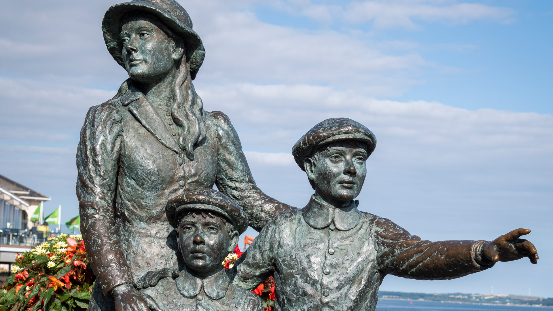 Bronze statue of woman and two children beside the sea at Cobh Heritage Centre
