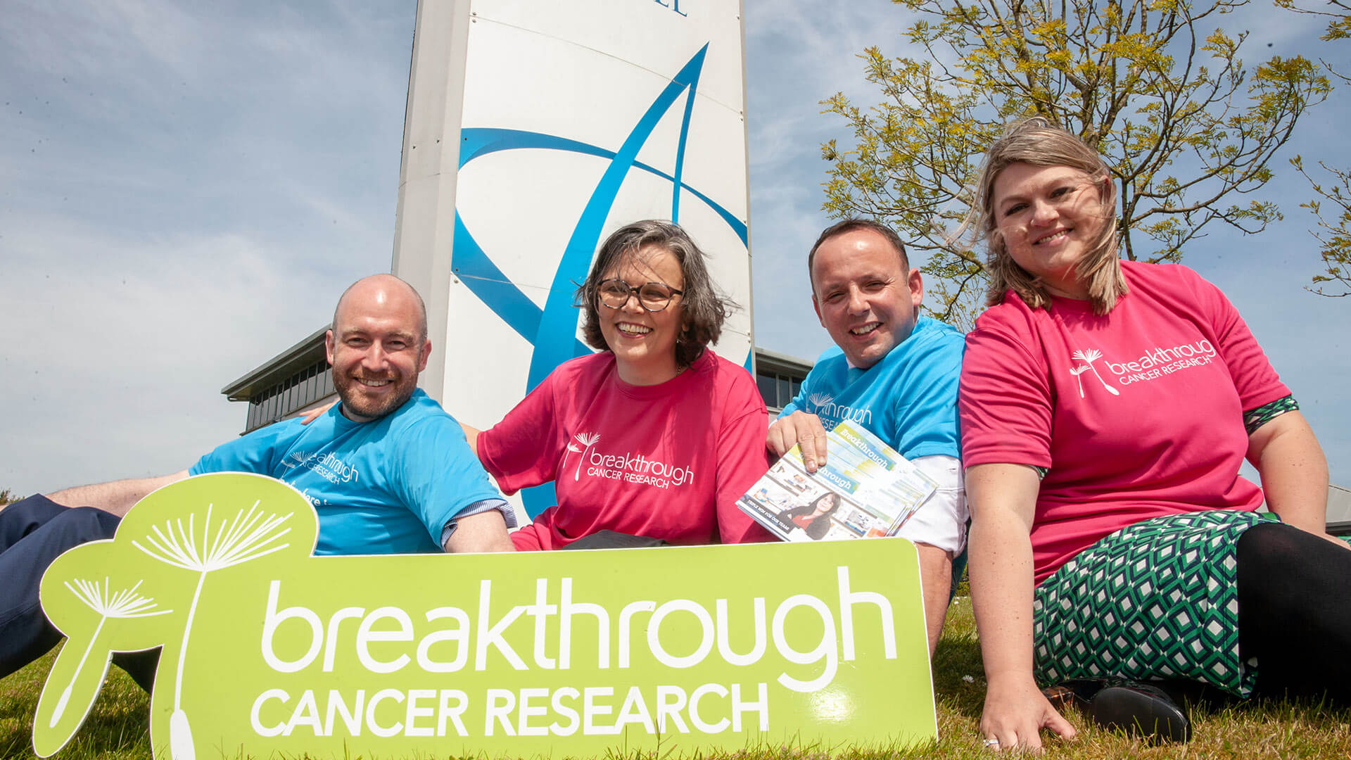 Four people holding a Cancer Research Breakthrough sign in front of the Cork Airport Hotel sign