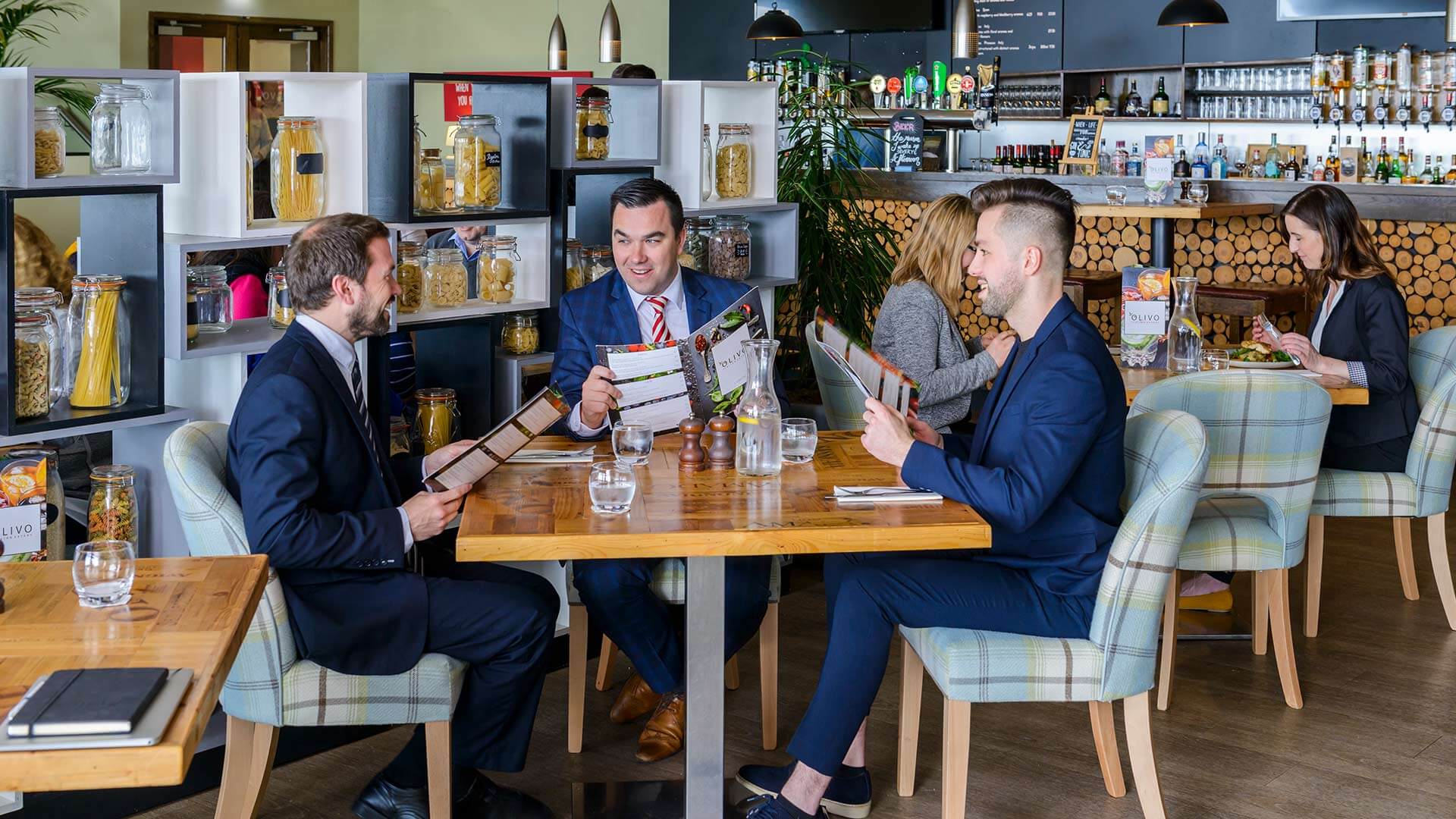 three men sitting at a table at the Olivo Italian Restaurant looking at menus