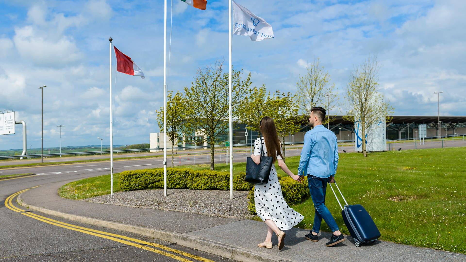 couple with suitcase wheelie bag walking outside Cork Airport Hotel